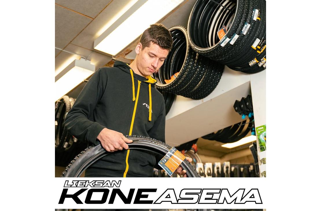 Nuori mies tutkii polkupyörän nastarengasta myymälässä rengashyllyjen edessä. Kuvan alalaidassa on Lieksan Koneasema -tekstilogo.