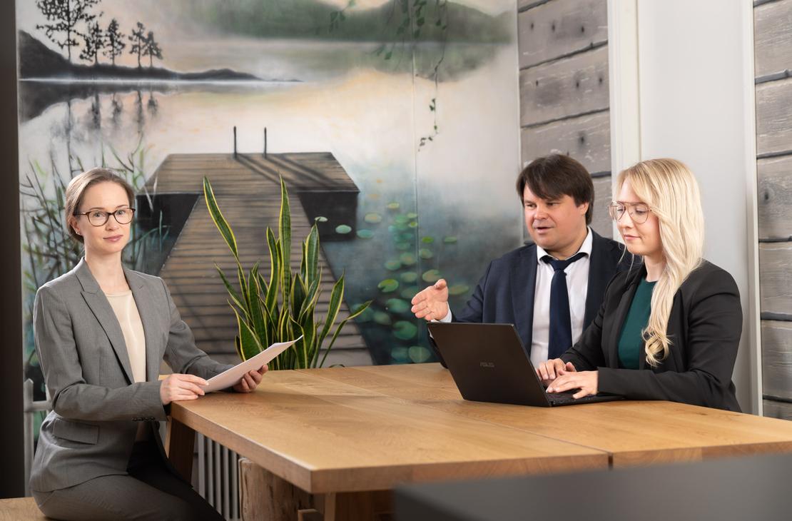 Teräskulman asianajotoimiston henkilöt istumassa ja keskustelemassa pöydän ääressä.