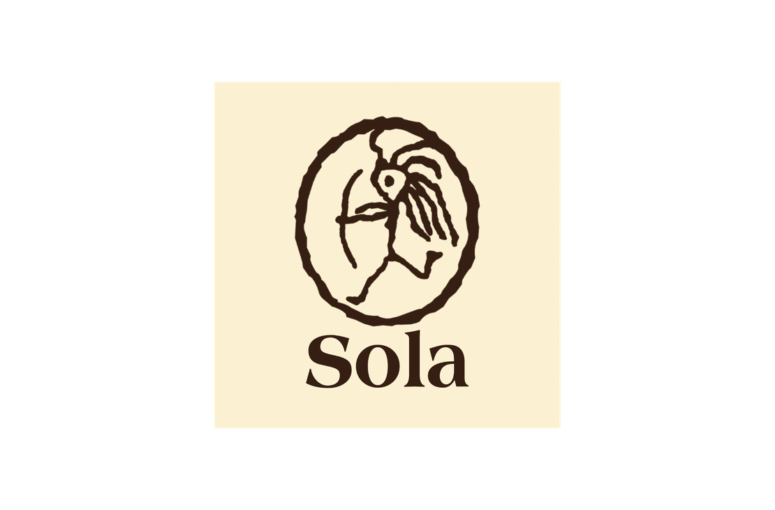 Sola Saippua Oy -yrityksen logo. Logossa on yläosassa pyöreän kehän sisällä oleva tummanruskea, tyylitelty kuvio, joka muistuttaa kalliomaalausta tai esihistoriallista kuviota, esittäen mahdollisesti ihmishahmoa ja lintua tai tyyliteltyä eläintä. Kuvion alla lukee tummanruskealla, serif-fontilla sana "Sola". Logo on vaalean beigellä taustalla.