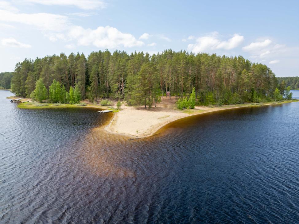 Korkealta otettu ilmakuva hiekkasärkän kärjestä ja sitä ympäröivästä järvestä. Niemenkärjessä kasvaa mäntymetsää, ja maastossa erottuu pieni punainen rakennus.