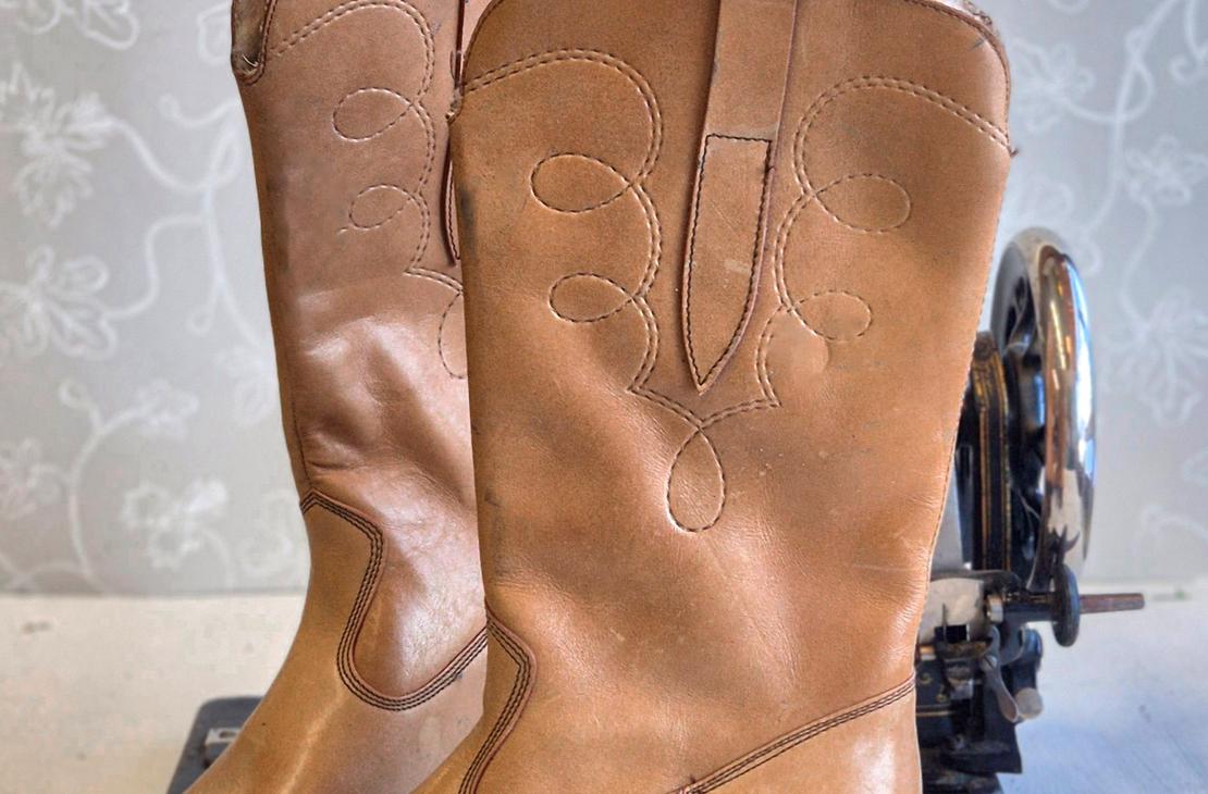 Pari klassisia, vaaleanruskeita nahkasaappaita, joissa on koristeellisia tikkauksia varressa ja maltillinen koro.