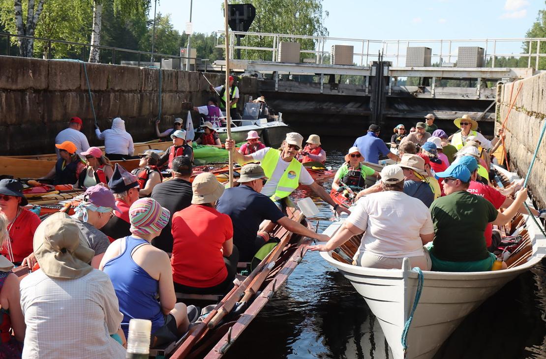 L&auml;hikuva kanavan sulussa olevista retkeilij&ouml;ist&auml;. Etualalla on kaksi puista soutuvenett&auml;, ja taustalla n&auml;kyy kanavan betoninen sulkuportti.