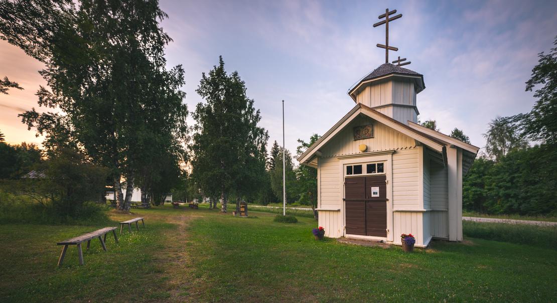 Pieni, punamultainen, perinteinen puurakennus, joka on Hattuvaaran tsasouna (ortodoksinen kappeli), harjakattoineen ja pienine ikkunoineen. Tsasouna sijaitsee m&auml;ntymets&auml;n reunustamalla hiekka- tai soratiell&auml;.