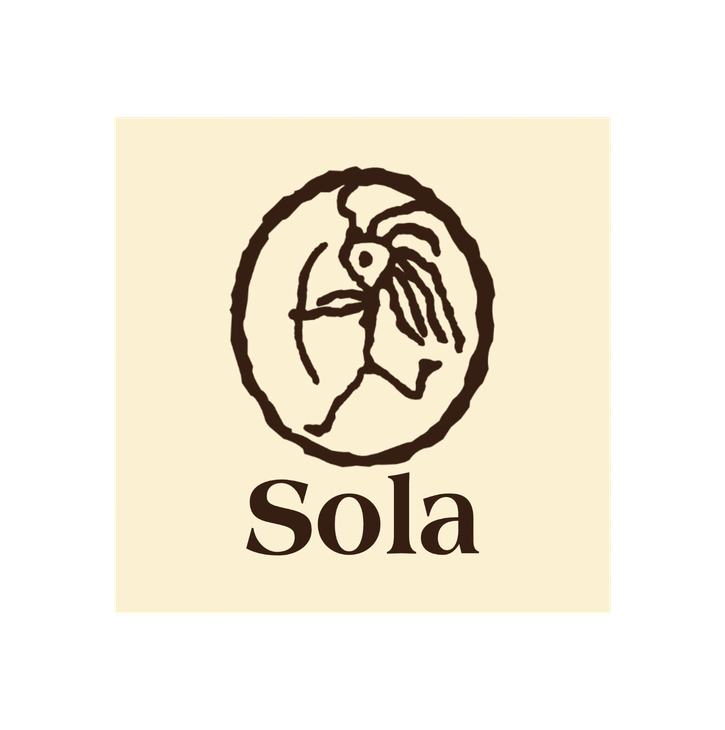 Sola Saippua Oy -yrityksen logo. Logossa on yläosassa pyöreän kehän sisällä oleva tummanruskea, tyylitelty kuvio, joka muistuttaa kalliomaalausta tai esihistoriallista kuviota, esittäen mahdollisesti ihmishahmoa ja lintua tai tyyliteltyä eläintä. Kuvion alla lukee tummanruskealla, serif-fontilla sana "Sola". Logo on vaalean beigellä taustalla.