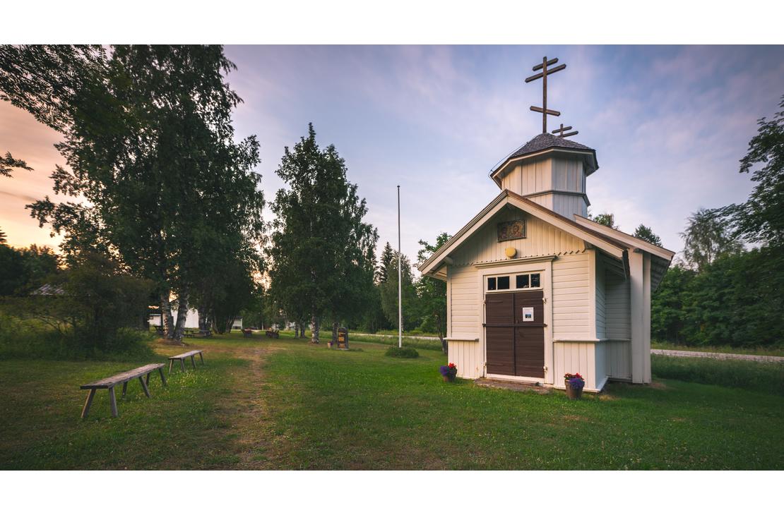 Pieni, punamultainen, perinteinen puurakennus, joka on Hattuvaaran tsasouna (ortodoksinen kappeli), harjakattoineen ja pienine ikkunoineen. Tsasouna sijaitsee mäntymetsän reunustamalla hiekka- tai soratiellä.