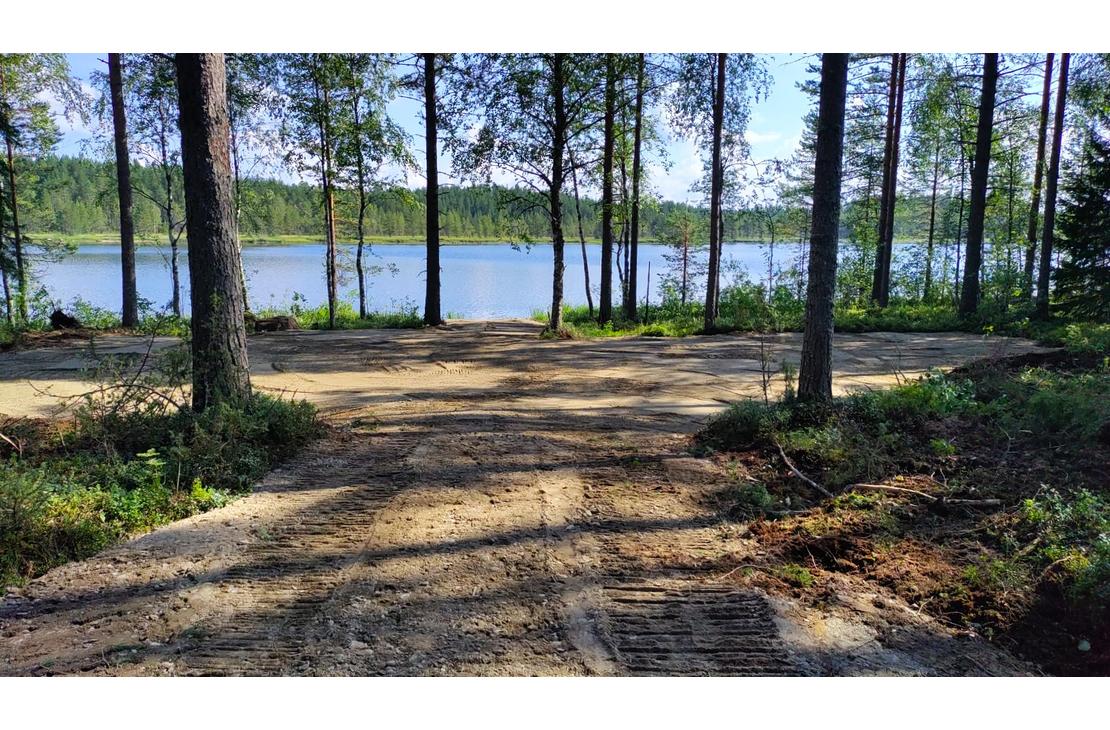 Kaivinkoneen kaivama tasainen tontin pohja j&auml;rven rannalla.