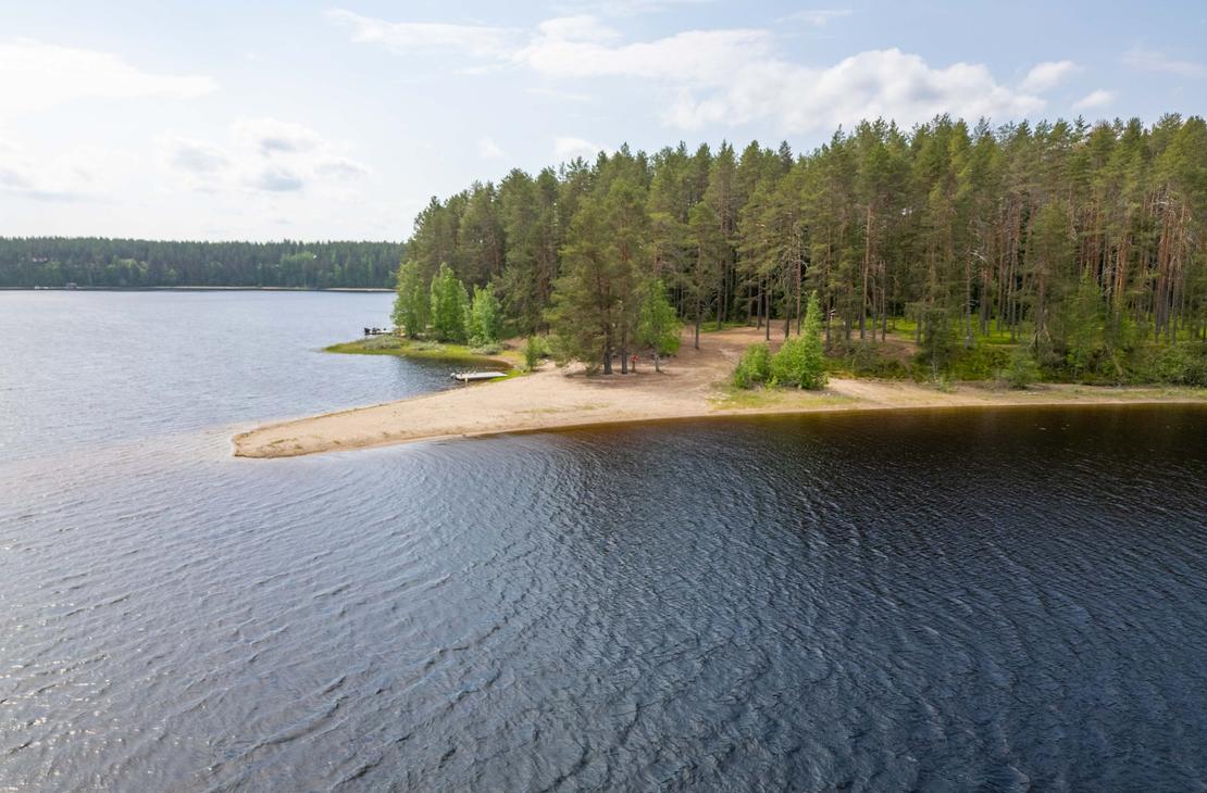 Ilmakuva järveen työntyvästä kapenevasta hiekkasärkystä, jota ympäröi kirkas ja tumma vesi. Särkän tyvellä kasvava mäntymetsä rehottaa vihreänä.
