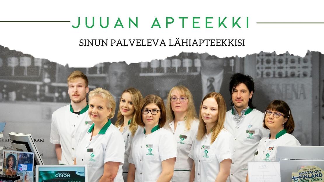 Ryhmäkuva Juuan Apteekin henkilökunnasta, jossa seitsemän naista ja kaksi miestä seisovat rivissä valkoisissa takeissa. Naiset etualalla ovat pukeutuneet valkoisiin takkeihin, joissa on vihreät kaulukset ja taskut. Taustalla on mustavalkoinen kuva tiilitalosta tai historiallisesta rakennuksesta. Kuvan yläosassa lukee vihreällä tekstillä "JUAN APTEEKKI" ja alapuolella pienemmällä tekstillä "SINUN PALVELEVA LÄHIAPTEEKKISI".