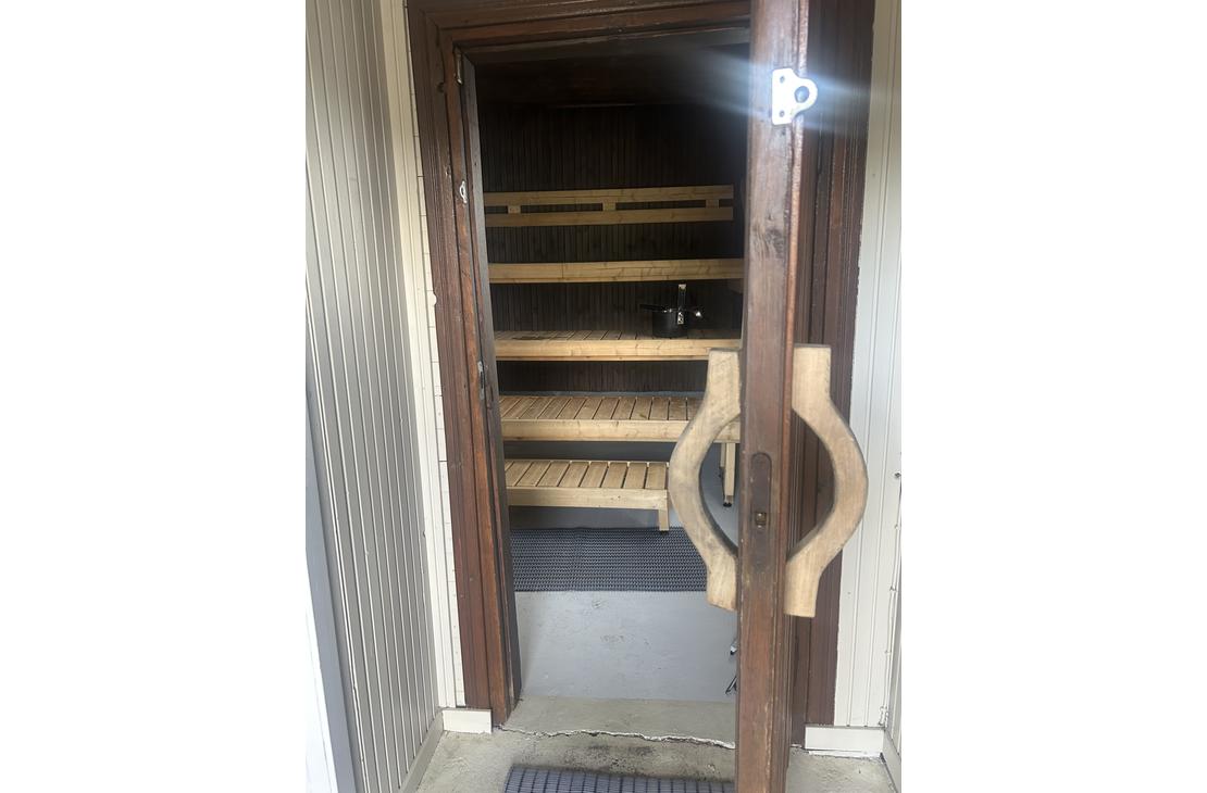 Näkymä saunan ovelta sisään, jossa näkyvät vaaleat puulauteet ja hämärä tunnelmavalaistus.