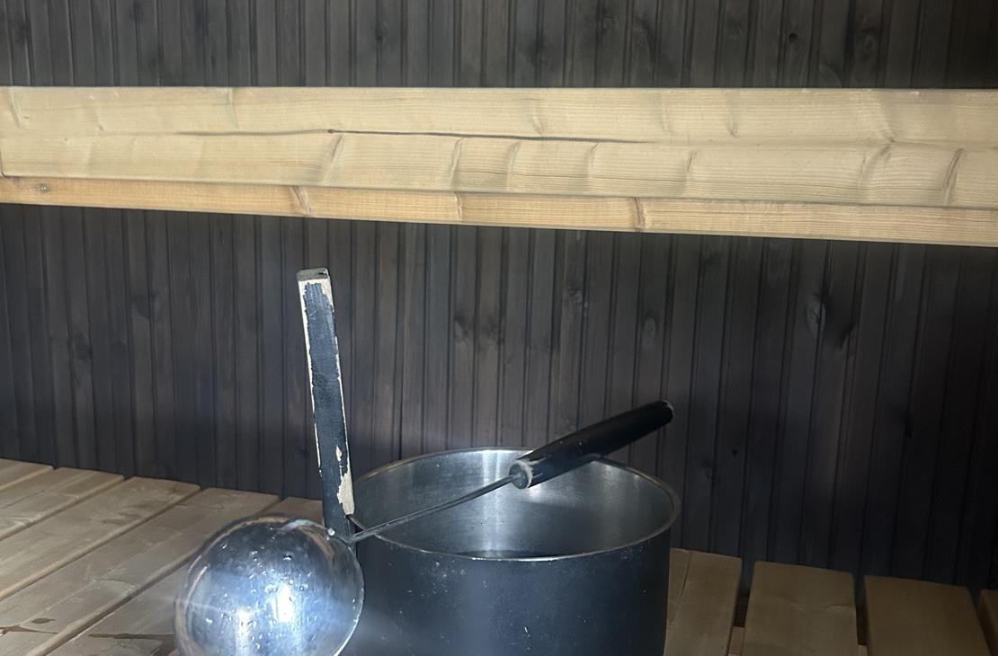 Metallinen saunakiulu ja löylykauha perinteisen puusaunan lauteilla.