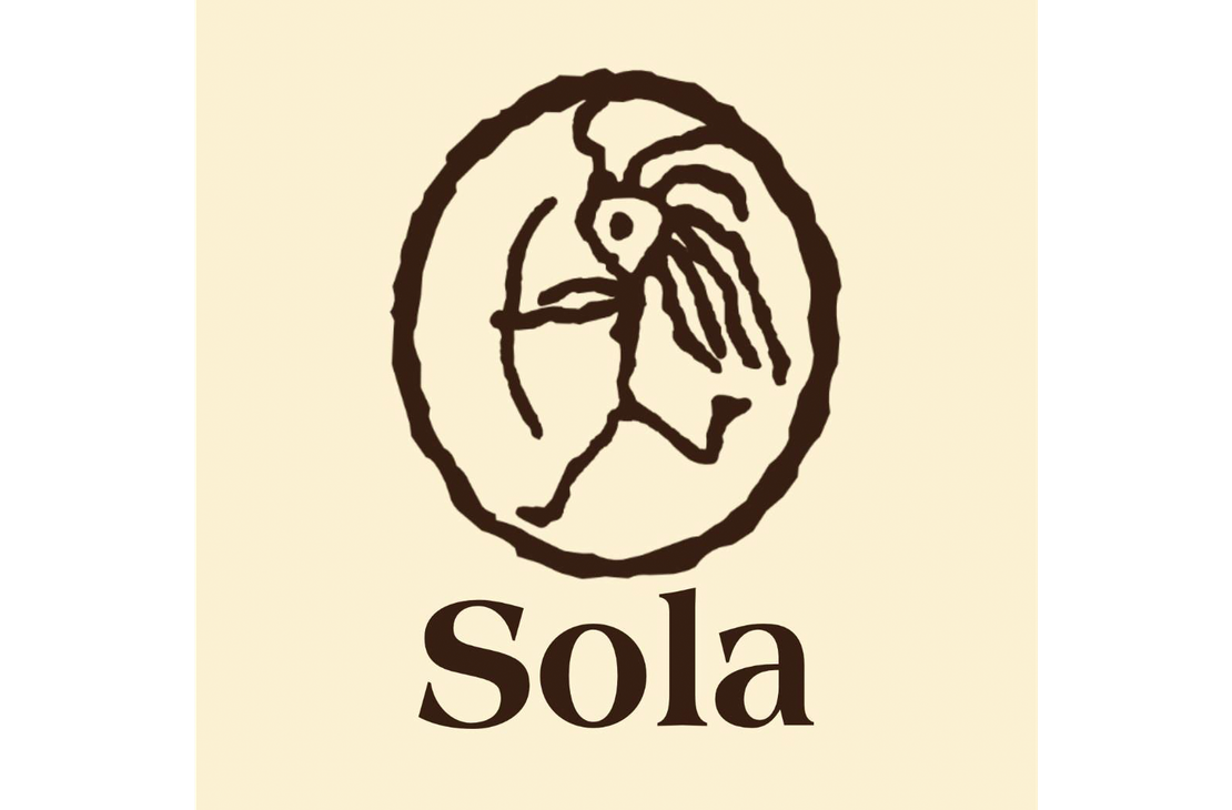 Sola Saippua Oy -yrityksen logo. Logossa on yläosassa pyöreän kehän sisällä oleva tummanruskea, tyylitelty kuvio, joka muistuttaa kalliomaalausta tai esihistoriallista kuviota, esittäen mahdollisesti ihmishahmoa ja lintua tai tyyliteltyä eläintä. Kuvion alla lukee tummanruskealla, serif-fontilla sana "Sola". Logo on vaalean beigellä taustalla.