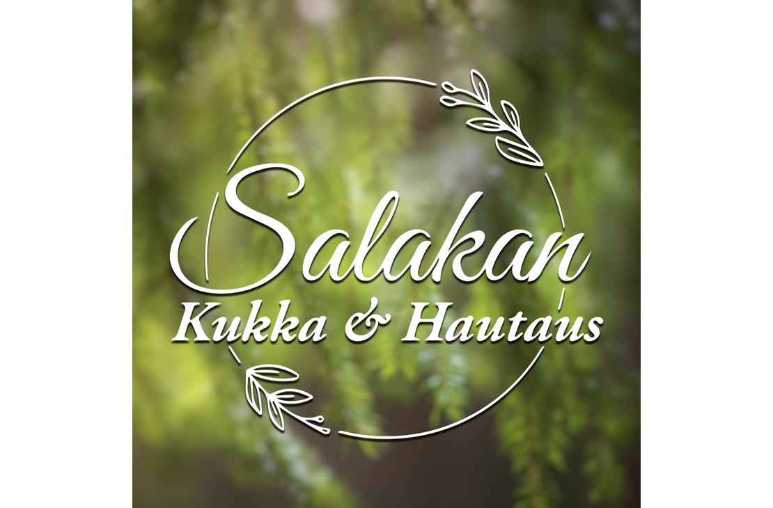 Salakan Kukka & Hautaus -yrityksen logo. Logossa on valkoinen, pyöreä kehys, jota koristaa kaksi tyyliteltyä lehti- tai oksapiirrosta. Kehyksen sisällä on valkoisella, kursivoidulla ja koristeellisella fontilla teksti: ylärivillä suuremmalla fontilla "Salakan" ja alarivillä pienemmällä fontilla "Kukka & Hautaus". Kuvan taustalla on epätarkka, pehmeä, vihreä kuva havunneulasista tai kasvillisuudesta.