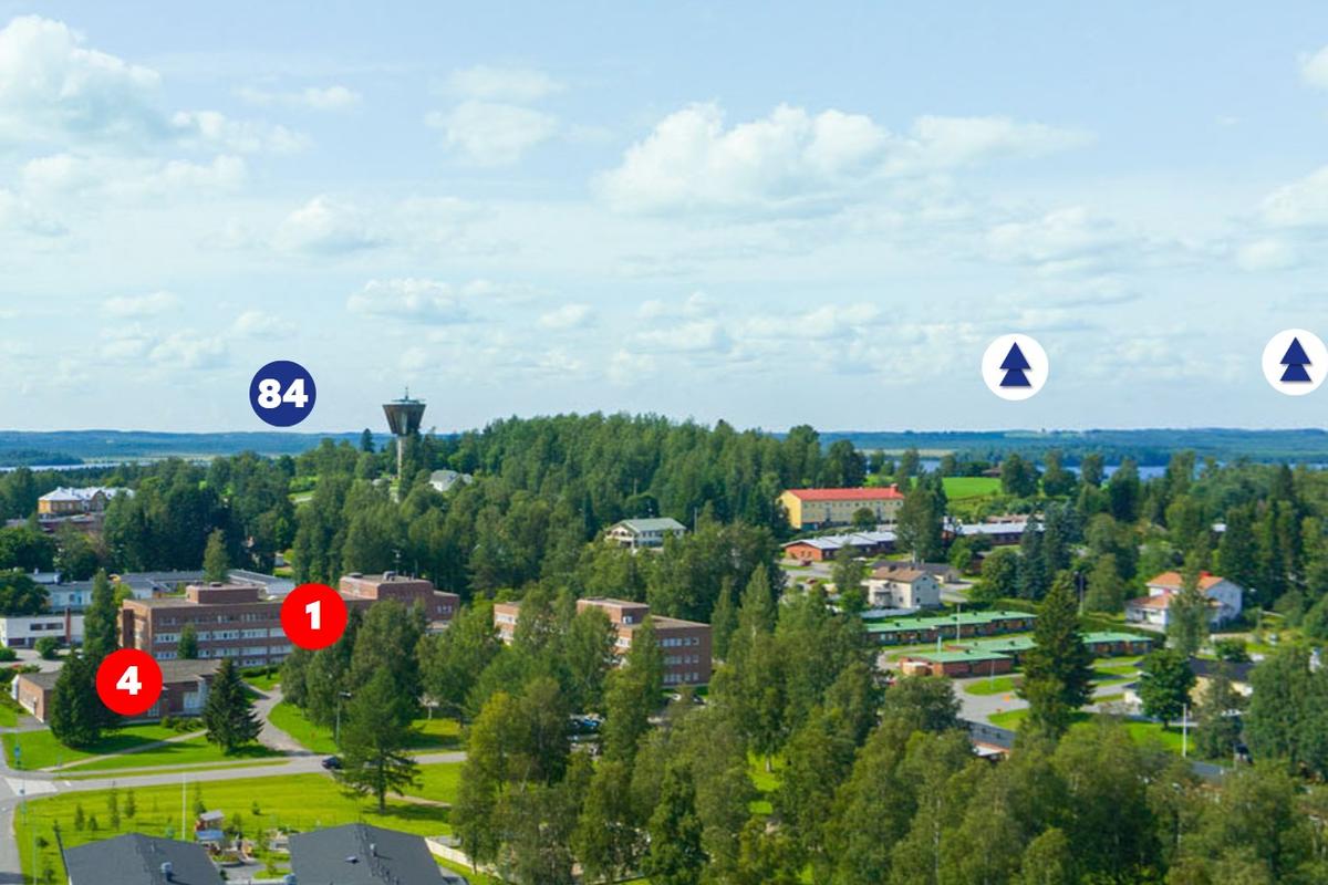 Ilmakuva 360 Palvelukartasta, joka näyttää kirkonkylää metsien ja järvimaiseman keskellä. Kuvaan on merkitty kohteita punaisilla numeroympyröillä (1, 4), sinisellä numeroympyrällä (84) sekä puukuvakkeilla. Taustalla näkyy vesitorni.