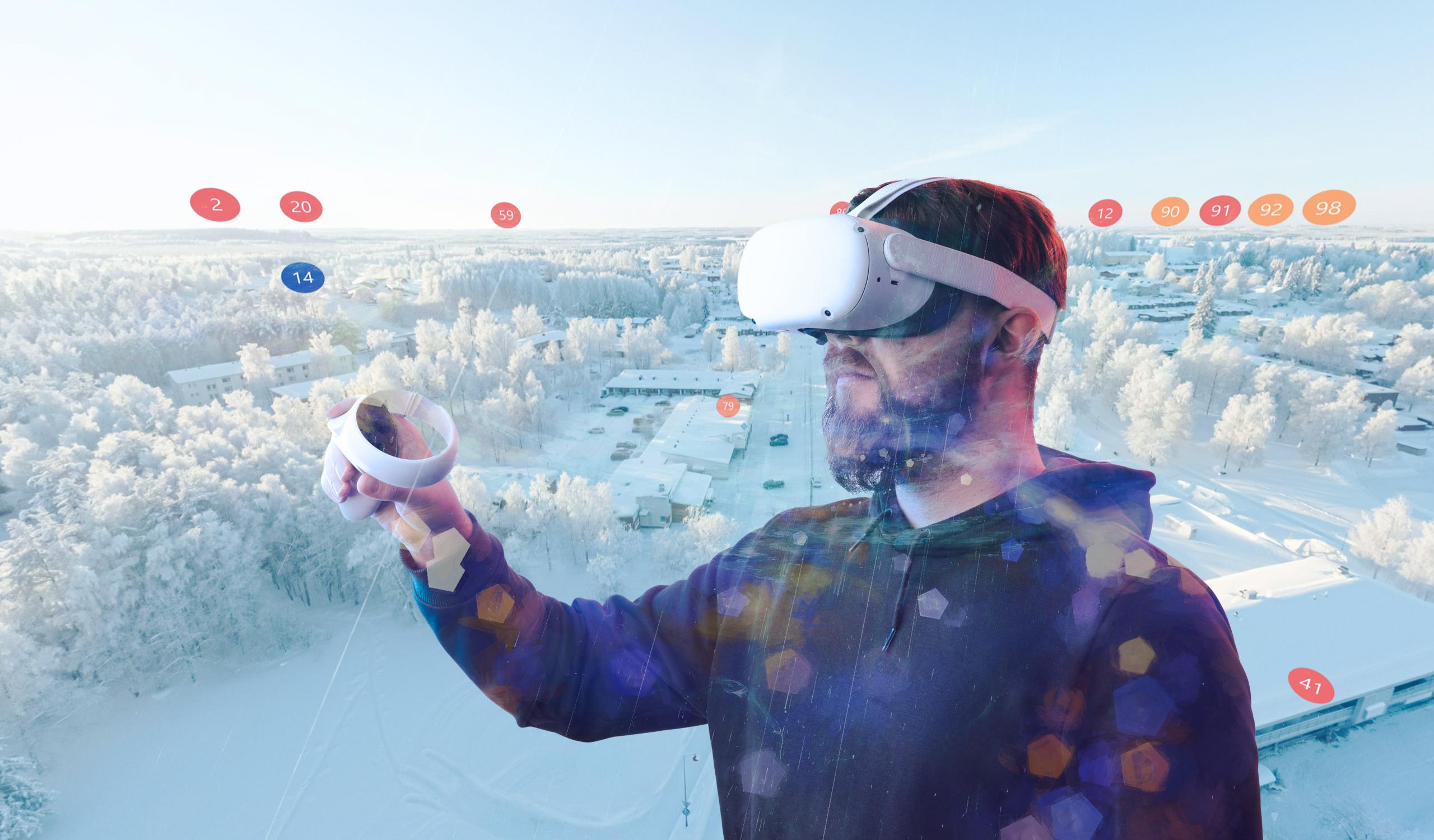 Parrakas mies k&auml;ytt&auml;&auml; VR-laseja ja pitelee ohjainta k&auml;dess&auml;&auml;n. H&auml;n on osittain l&auml;pikuultava, ja h&auml;nen taustanaan on ilmakuva lumisesta, huurteisesta asuinalueesta. 360 Palvelukartan virtuaalisia, numeroituja punaisia ja sinisi&auml; palloja leijuu maiseman yll&auml;.