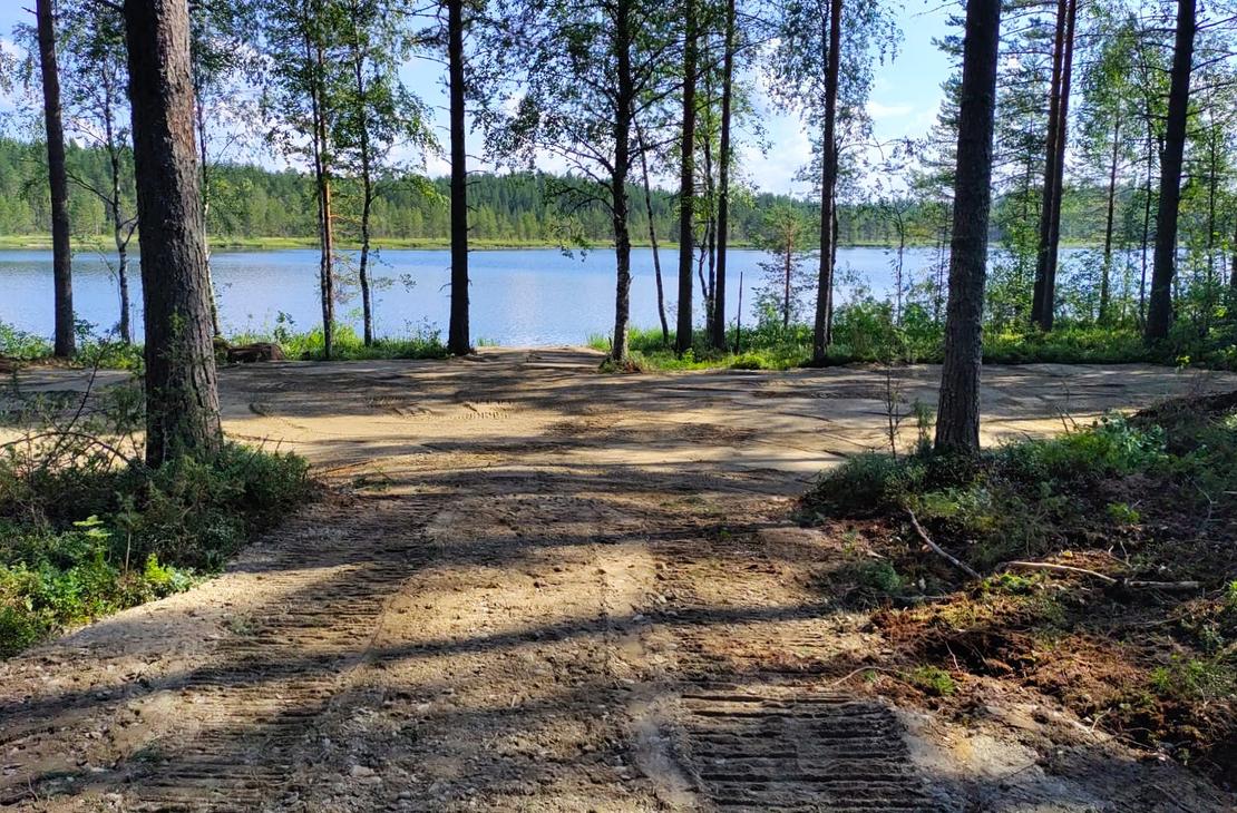 Kaivinkoneen kaivama tasainen tontin pohja järven rannalla.
