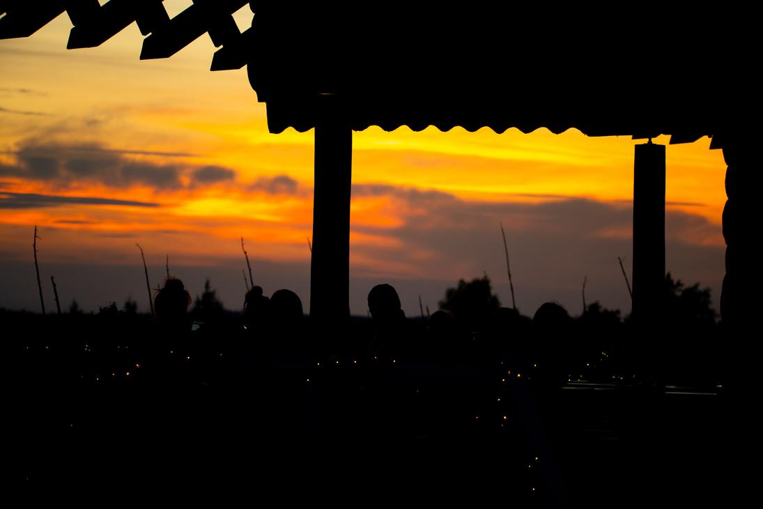Ravintola Parppeinpirtti, Ihmisten ja rakennuksen katon siluetteja voimakkaan oranssinkeltaista auringonlaskun taivasta vasten.