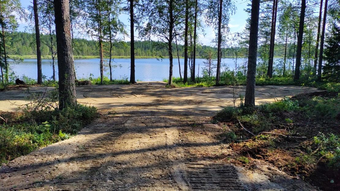 Kaivinkoneen kaivama tasainen tontin pohja j&auml;rven rannalla.