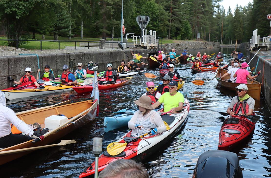 Kanava-allas t&auml;ynn&auml; v&auml;rikk&auml;it&auml; kajakkeja, kanootteja ja soutuveneit&auml; odottamassa sulutusta. Retkeilij&ouml;ill&auml; on yll&auml;&auml;n kelluntaliivit.