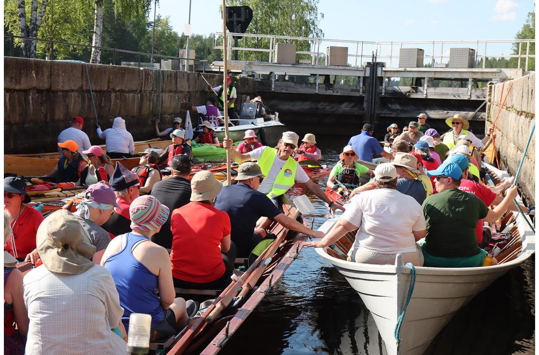 L&auml;hikuva kanavan sulussa olevista retkeilij&ouml;ist&auml;. Etualalla on kaksi puista soutuvenett&auml;, ja taustalla n&auml;kyy kanavan betoninen sulkuportti.