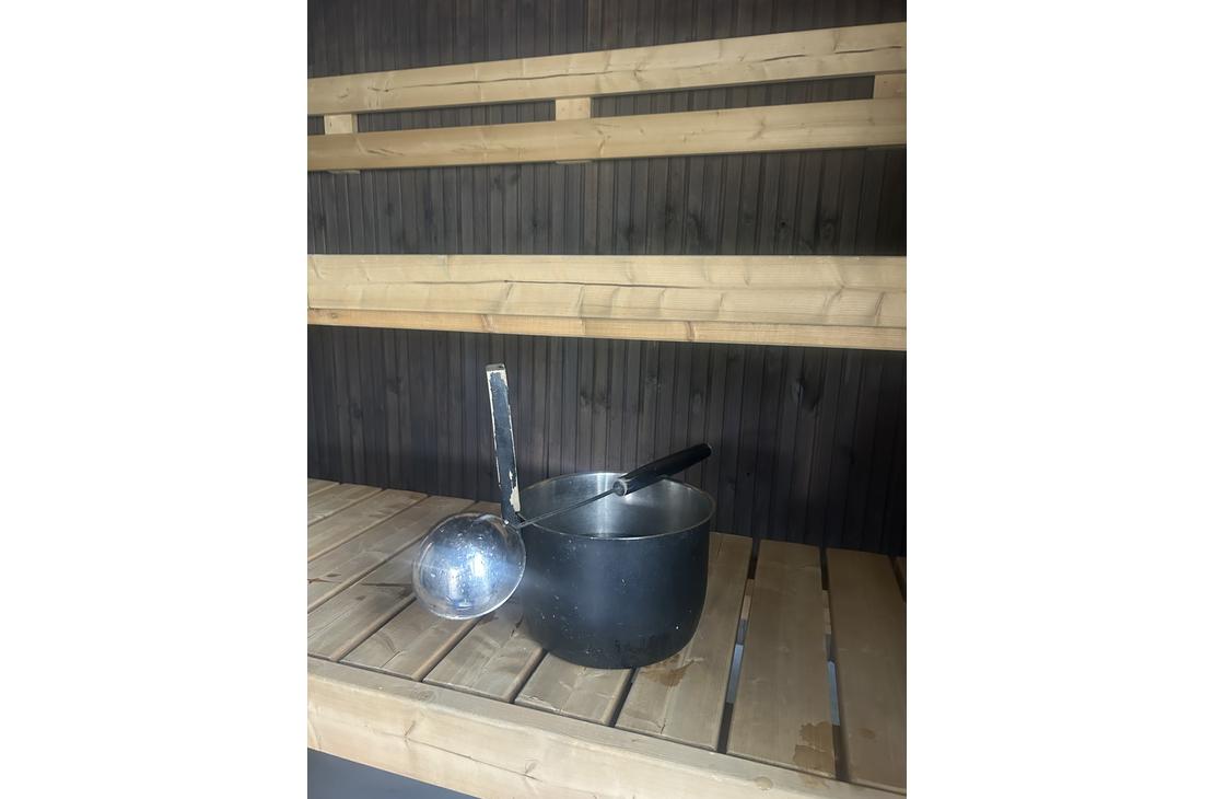 Metallinen saunakiulu ja löylykauha perinteisen puusaunan lauteilla.
