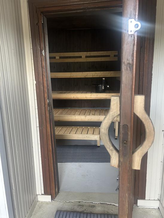 Näkymä saunan ovelta sisään, jossa näkyvät vaaleat puulauteet ja hämärä tunnelmavalaistus.