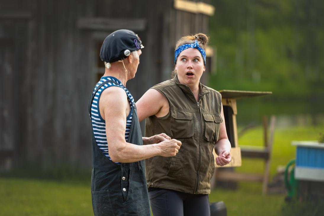 M&ouml;hk&ouml;n kes&auml;teatterin Peitetarina-n&auml;ytelm&auml;n kohtaus, jossa kaksi n&auml;yttelij&auml;&auml; esiintyy ulkon&auml;ytt&auml;m&ouml;ll&auml; vanhan puurakennuksen edustalla. Vasemmalla on raidalliseen hihattomaan paitaan, haalareihin ja mustaan p&auml;&auml;hineeseen pukeutunut mies sivuprofiilissa. Oikealla oleva nainen, jolla on sininen p&auml;&auml;huivi ja vihre&auml; liivi, katsoo miest&auml; &auml;&auml;rimm&auml;isen h&auml;mm&auml;styneen&auml; suu ammollaan.