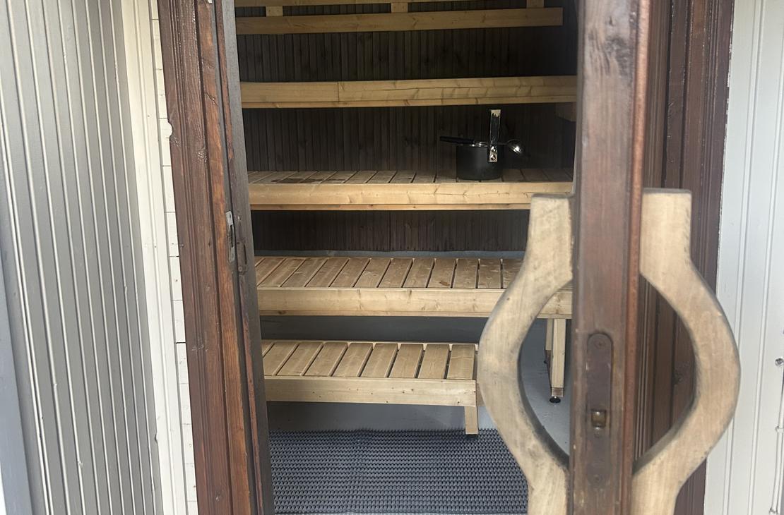 Näkymä saunan ovelta sisään, jossa näkyvät vaaleat puulauteet ja hämärä tunnelmavalaistus.