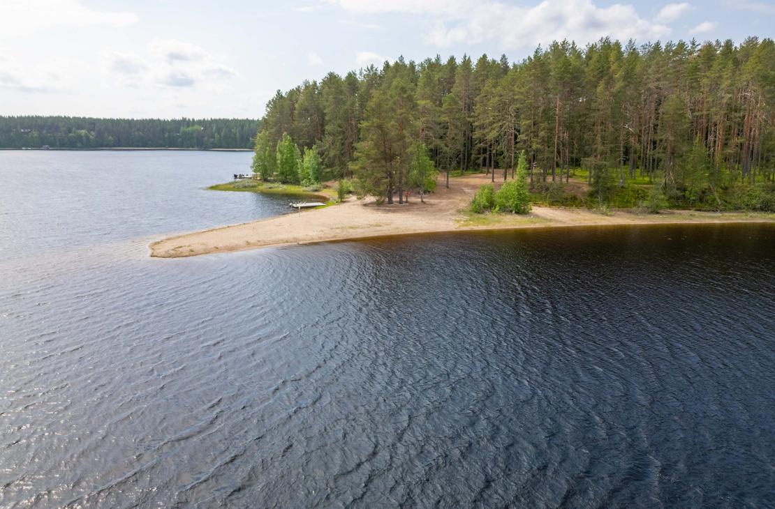 Ilmakuva järveen työntyvästä kapenevasta hiekkasärkystä, jota ympäröi kirkas ja tumma vesi. Särkän tyvellä kasvava mäntymetsä rehottaa vihreänä.