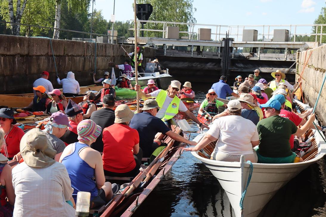 L&auml;hikuva kanavan sulussa olevista retkeilij&ouml;ist&auml;. Etualalla on kaksi puista soutuvenett&auml;, ja taustalla n&auml;kyy kanavan betoninen sulkuportti.