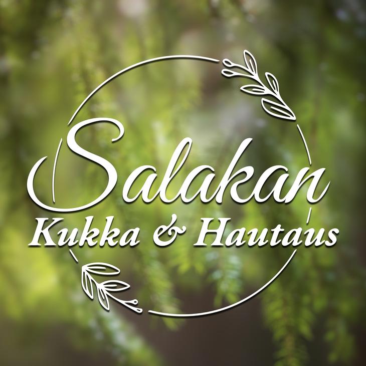 Salakan Kukka & Hautaus -yrityksen logo. Logossa on valkoinen, pyöreä kehys, jota koristaa kaksi tyyliteltyä lehti- tai oksapiirrosta. Kehyksen sisällä on valkoisella, kursivoidulla ja koristeellisella fontilla teksti: ylärivillä suuremmalla fontilla "Salakan" ja alarivillä pienemmällä fontilla "Kukka & Hautaus". Kuvan taustalla on epätarkka, pehmeä, vihreä kuva havunneulasista tai kasvillisuudesta.