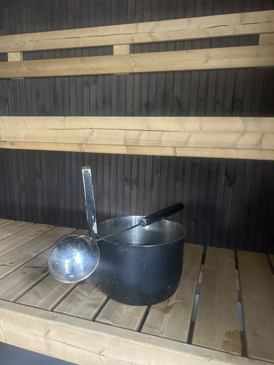 Metallinen saunakiulu ja löylykauha perinteisen puusaunan lauteilla.